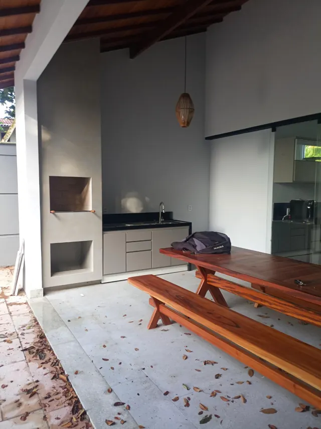 Área gourmet com churrasqueira e mesa de madeira